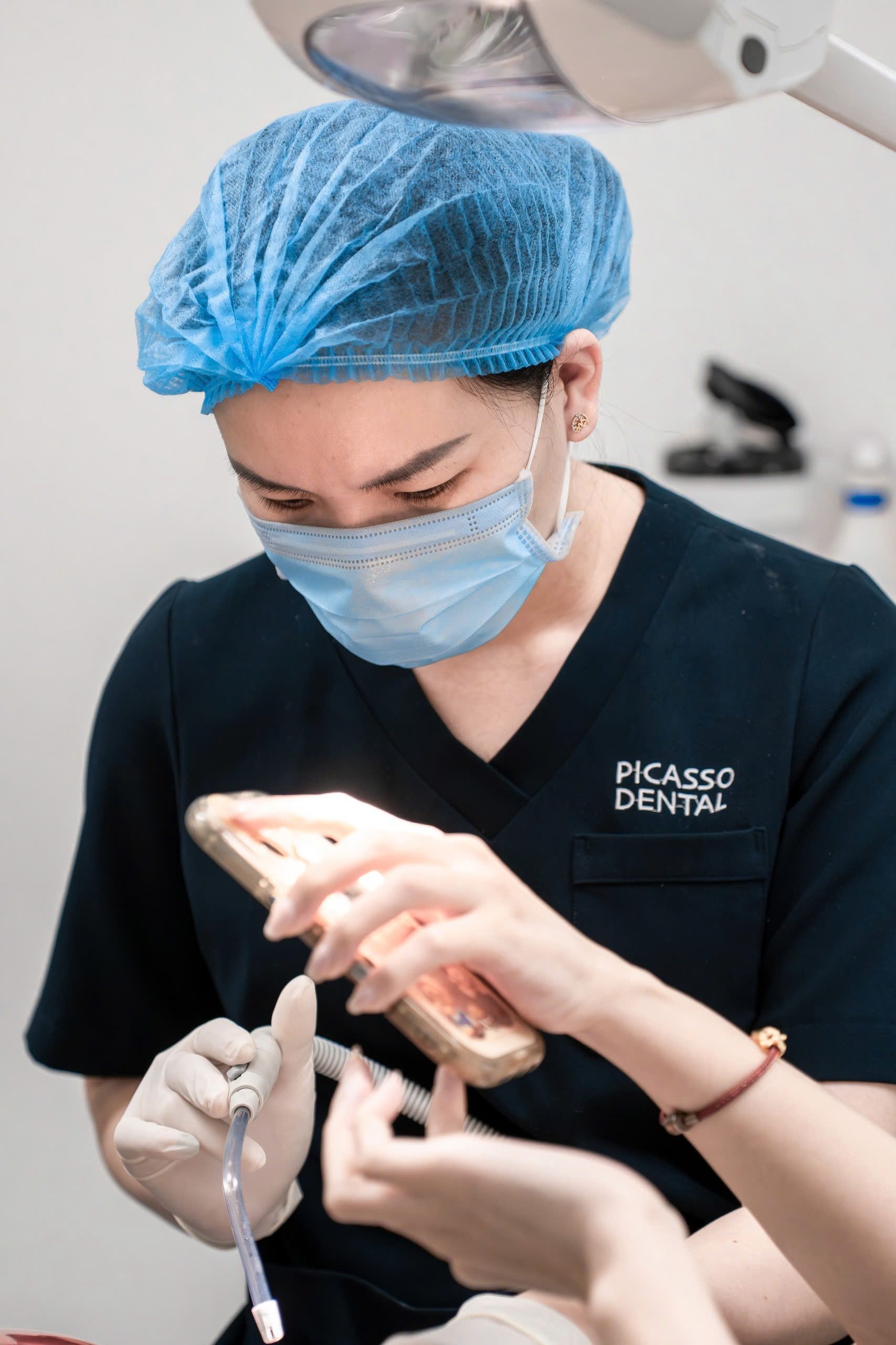 Nurse preparing instruments during dental procedure at Picasso Dental